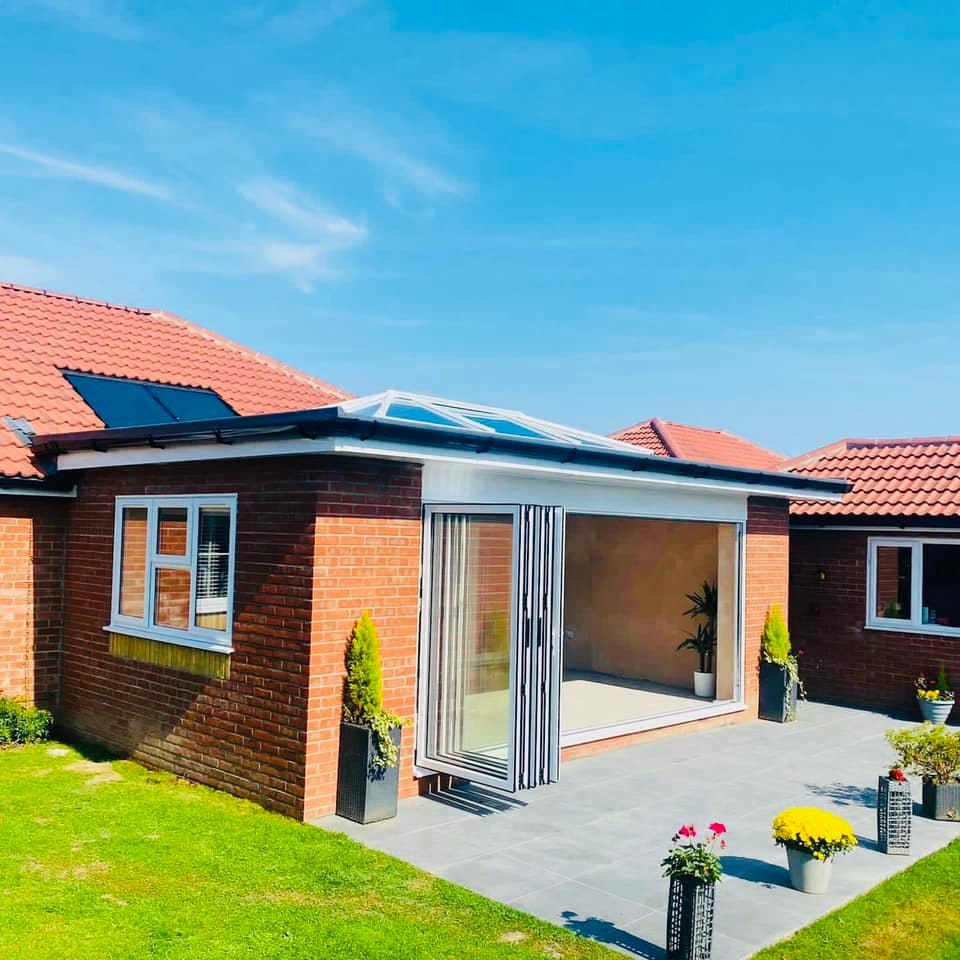 Anthracite aluminium bifold doors open onto the garden of a brick bungalow extension