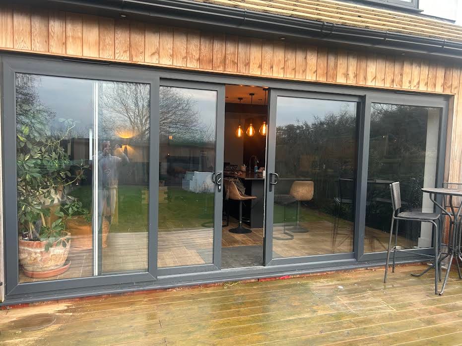 Black aluminium sliding patio doors on a cedar-clad extension