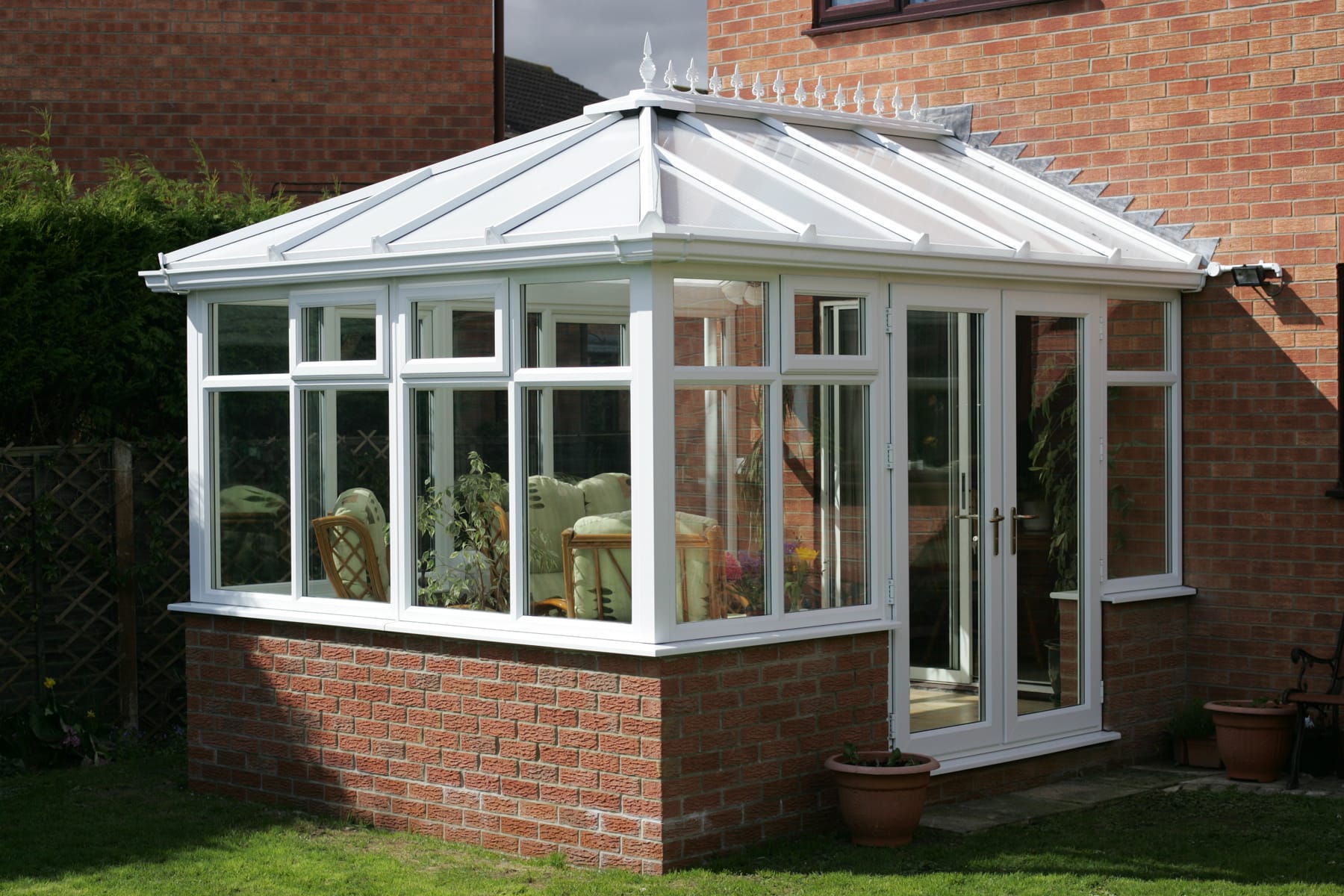 White uPVC Edwardian conservatory with a glass roof in a garden