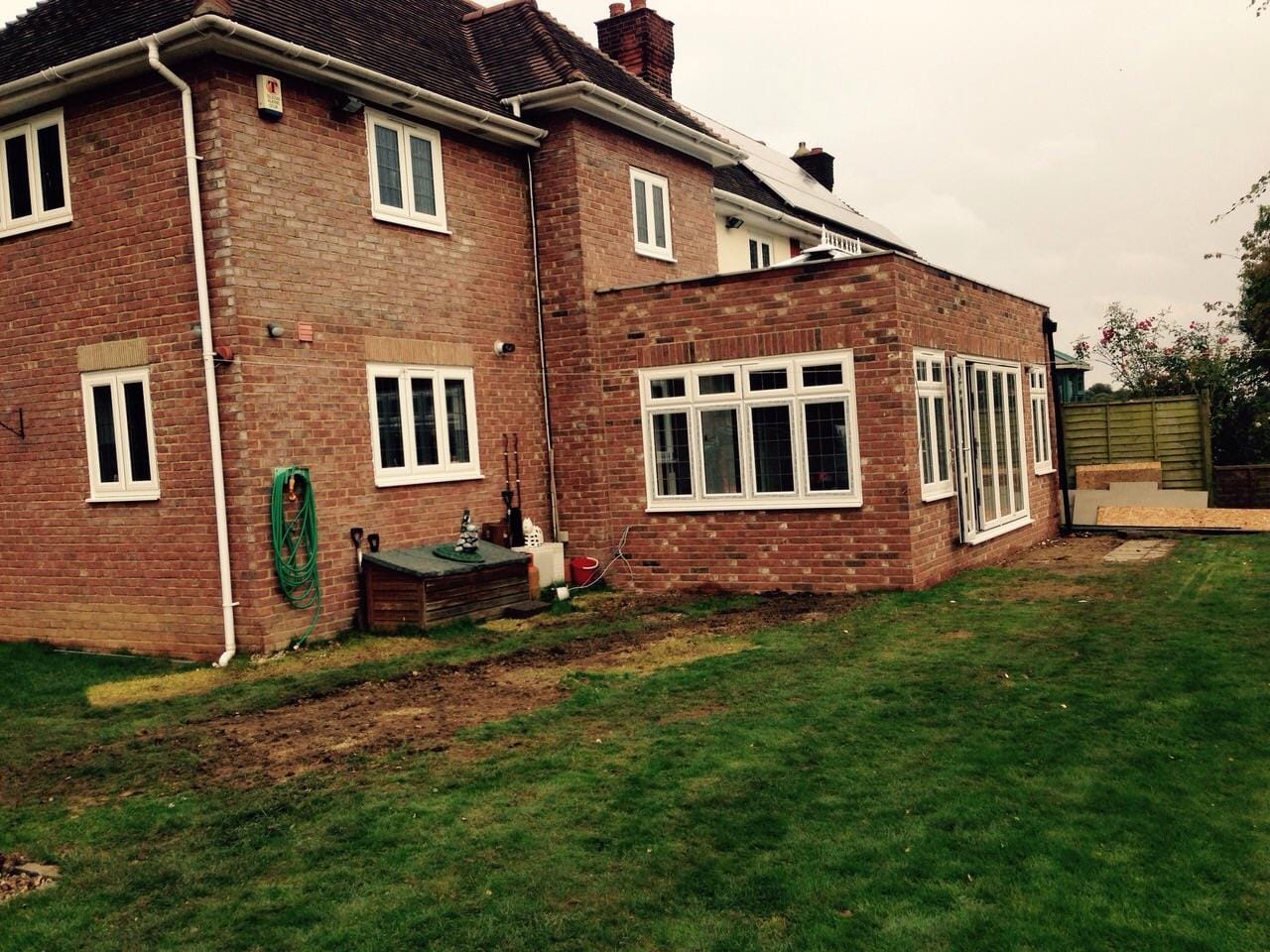 New white uPVC windows fitted to the rear of a red-brick semi-detached house
