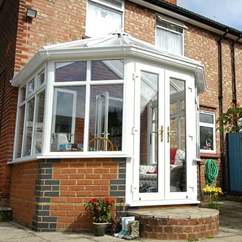 White uPVC Victorian conservatory on a red-brick house